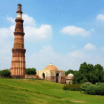 Qutub Minar, the 72.5-meter-tall red sandstone minaret in Delhi, India, with intricate carvings and balconies, set against a blue sky