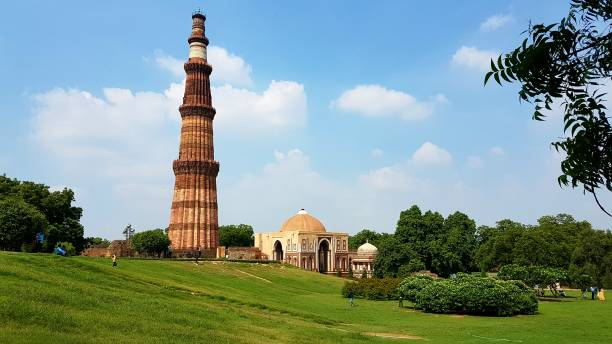 Qutub Minar, the 72.5-meter-tall red sandstone minaret in Delhi, India, with intricate carvings and balconies, set against a blue sky